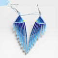 Aretes Huichol de chaquira, diseño triangular con flecos azules degradados y blanco.