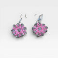 Aretes Huichol de chaquira, rosa y gris cristalino, con patrón floral geométrico.
