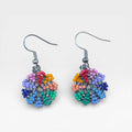 Aretes Wixárika de chaquira, patrón geométrico floral con azul, rojo y verde.