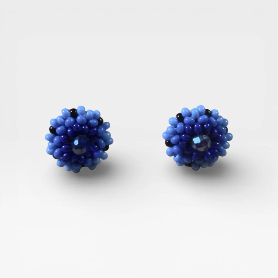 Aretes de chaquira Huichol/Wixárika, diseño floral en tonos azules y negro.