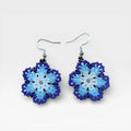 Aretes Wixárika de chaquira en tonos azules y blanco, con diseño floral.