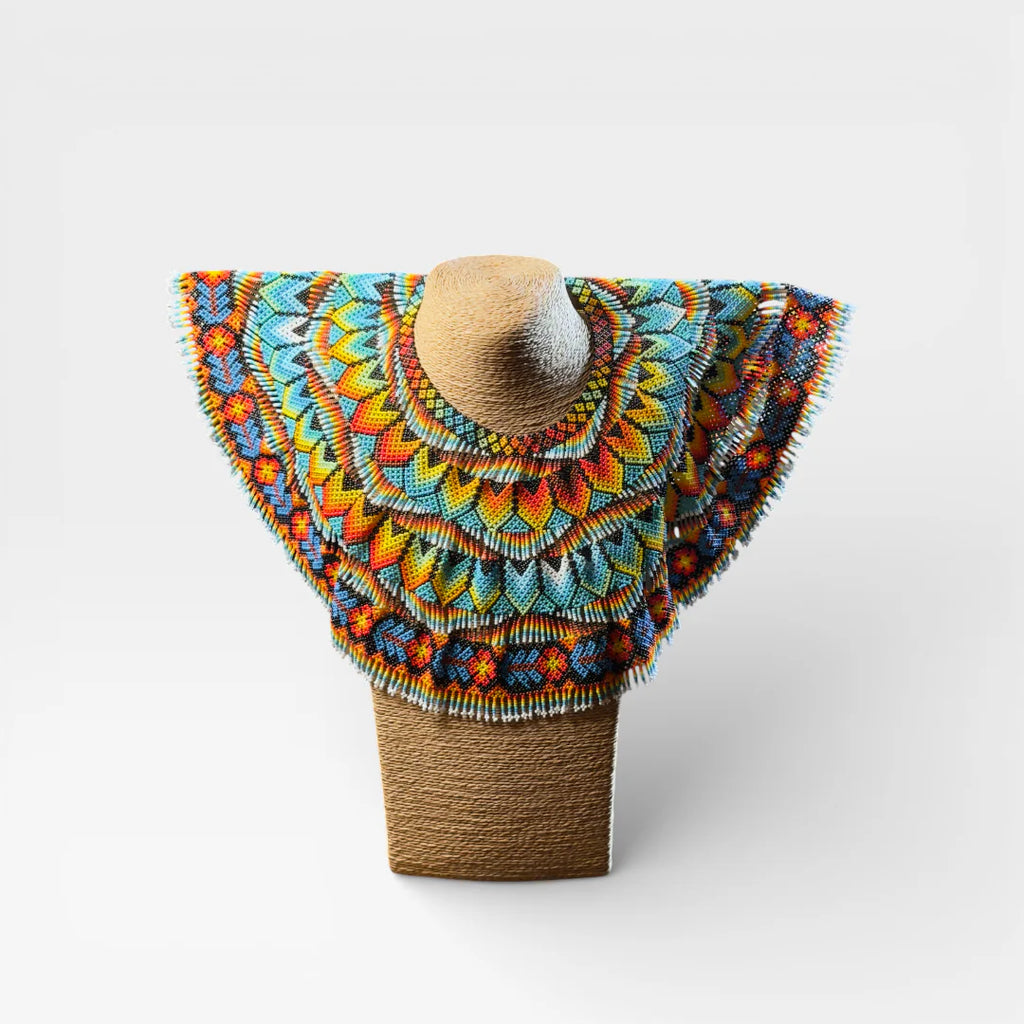 Collar Huichol con chaquira, diseño geométrico radial en azul, amarillo y naranja.
