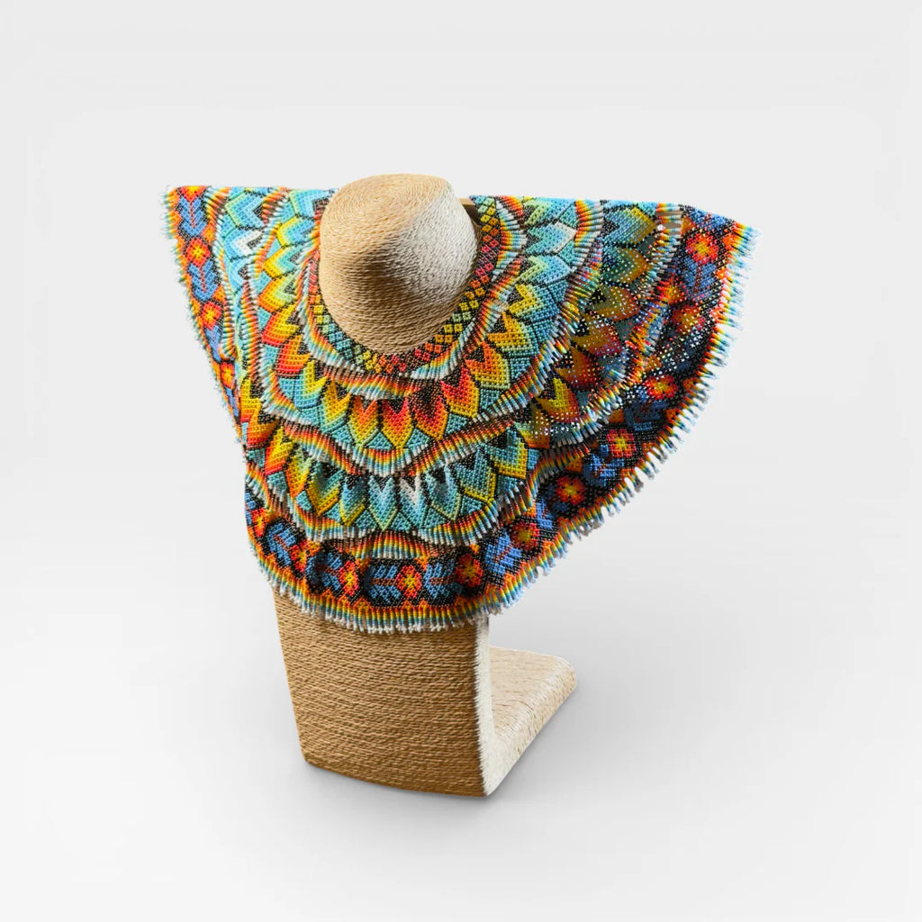Collar Huichol con chaquira, diseño geométrico radial en azul, amarillo y naranja.