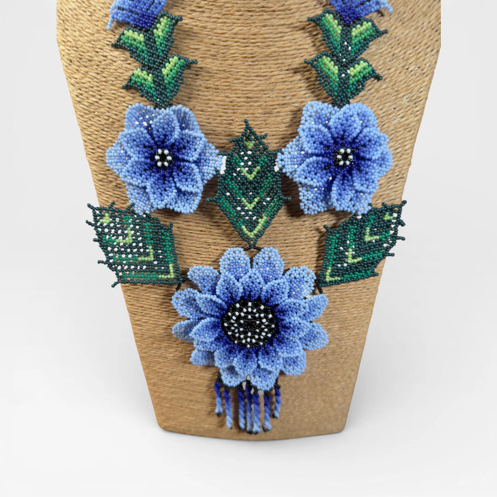 Collares: Chaquira Wixárika floral con flores azules y follaje verde vibrante.