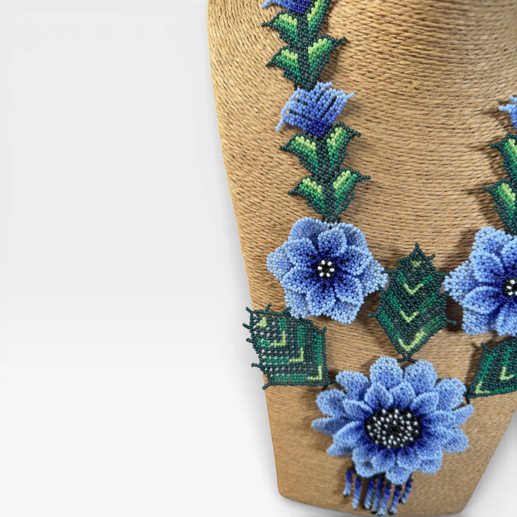 Collares: Chaquira Wixárika floral con flores azules y follaje verde vibrante.