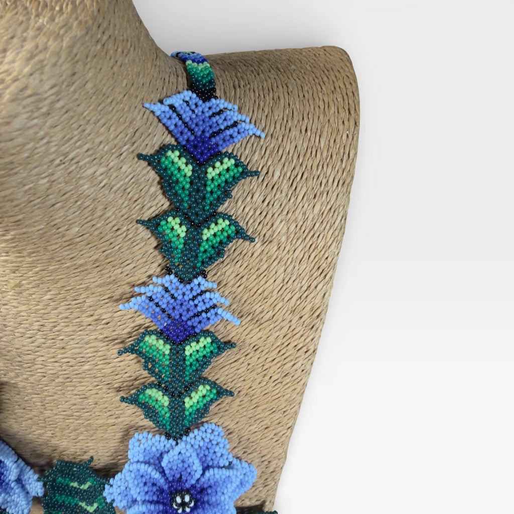 Collares: Chaquira Wixárika floral con flores azules y follaje verde vibrante.
