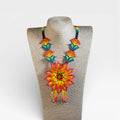 Collares: Collar Huichol de chaquira, flor central amarilla y naranja con detalles turquesa.