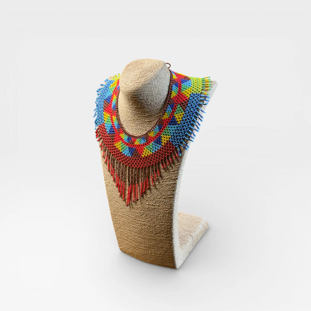 Collares: Pechera Wixárika de chaquira con patrón geométrico en rojo, azul y amarillo.