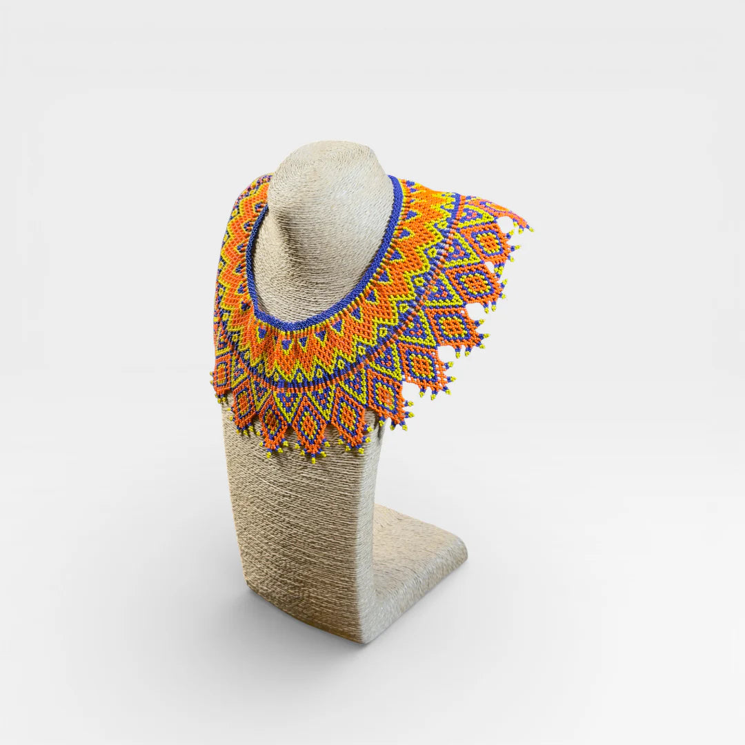 Collar Huichol de chaquira naranja, amarillo y azul con patrón de rombos geométricos.