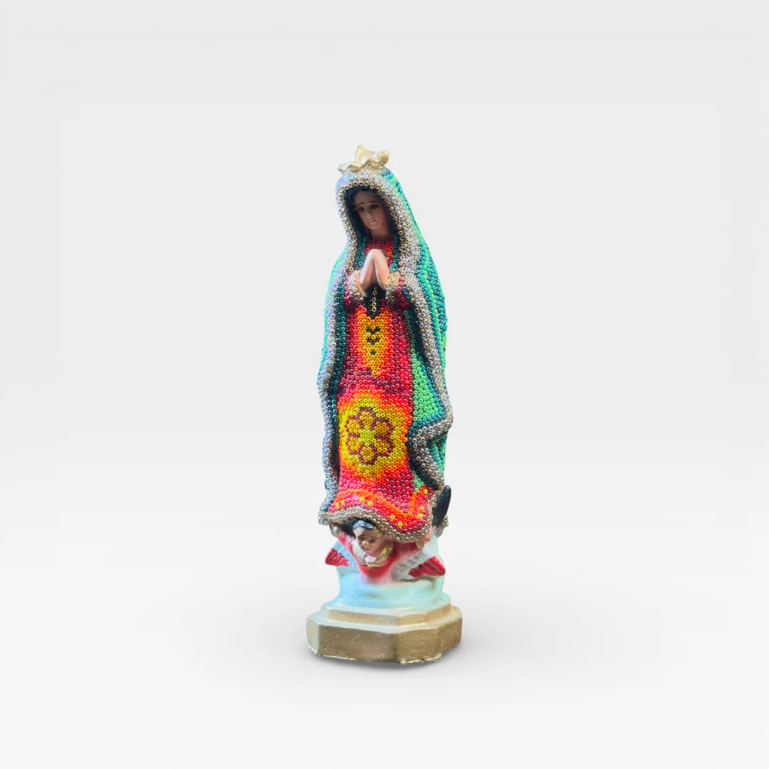 Figura de Chaquira Huichol: Virgen de Guadalupe verde, roja y amarilla con símbolo floral.
