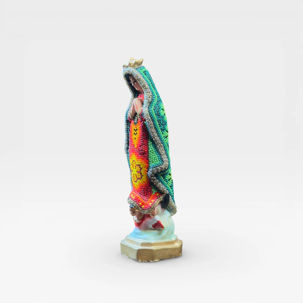 Figura de Chaquira Huichol: Virgen de Guadalupe verde, roja y amarilla con símbolo floral.