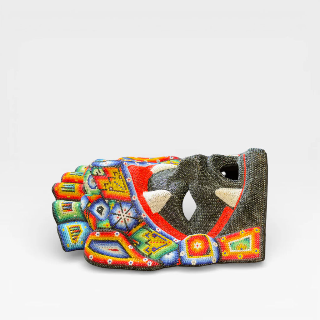 Figuras de Chaquira: Máscara Huichol con colmillos, rostro negro, boca roja y diseños vibrantes.